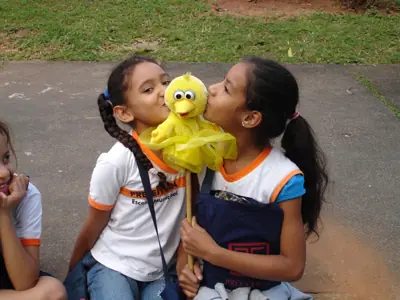 Duas crianças fazem carinho no Criu Carioca, mascote do projeto.